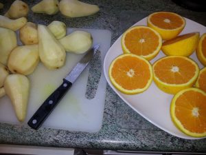 Pears and oranges on 2 chopping boards with knife